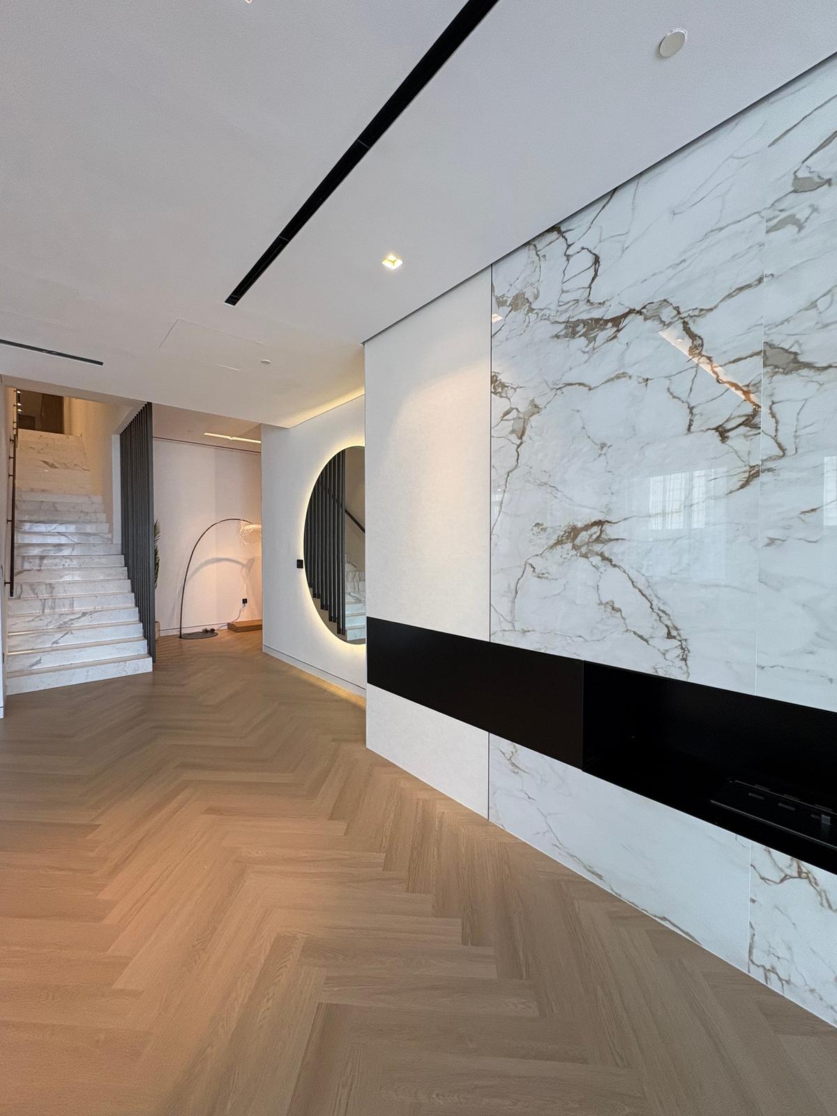 Marble feature wall, herringbone flooring and a lit arched opening